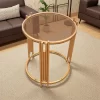 ترابيزة جانبية دائرية ذهبية اللون مع سطح زجاجي فيميه وتصميم معدني عصري لأي غرفة معيشة أو استقبال.
