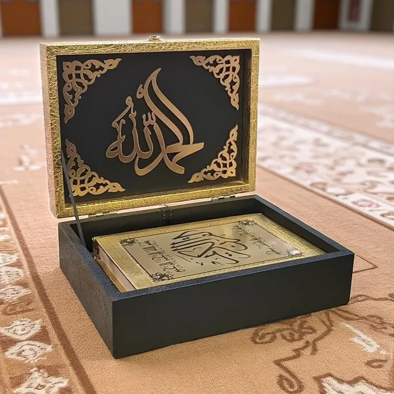 صندوق حفظ المصحف الفاخر مفتوح، يظهر كلمة الحمد لله بالخط الذهبي داخل الغطاء ومصحف ذهبي فاخر بالداخل، هدية إسلامية أنيقة.