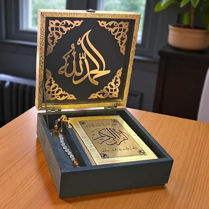 صندوق حفظ المصحف الشريف باللون الذهبي والأسود، مزين بنقوش "القرآن الكريم" وكريستالات لامعة، هدية إسلامية فاخرة.