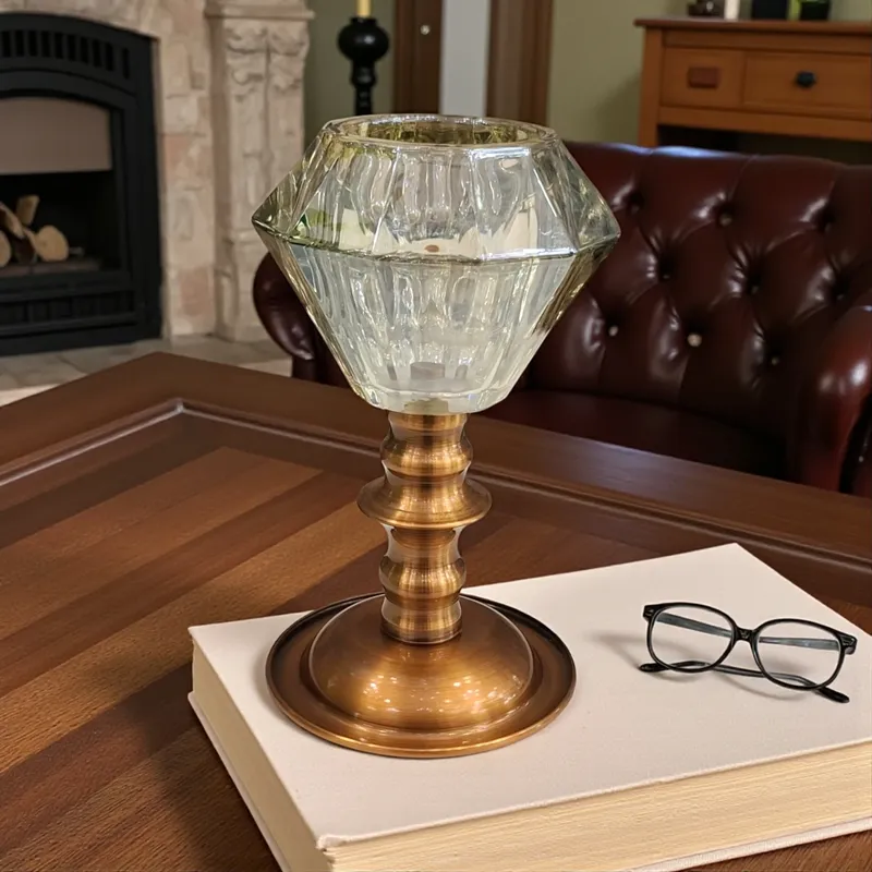 حامل شمع كريستالي على شكل ماسة بقاعدة نحاسية عتيقة موضوع على كتاب أبيض على طاولة خشبية.