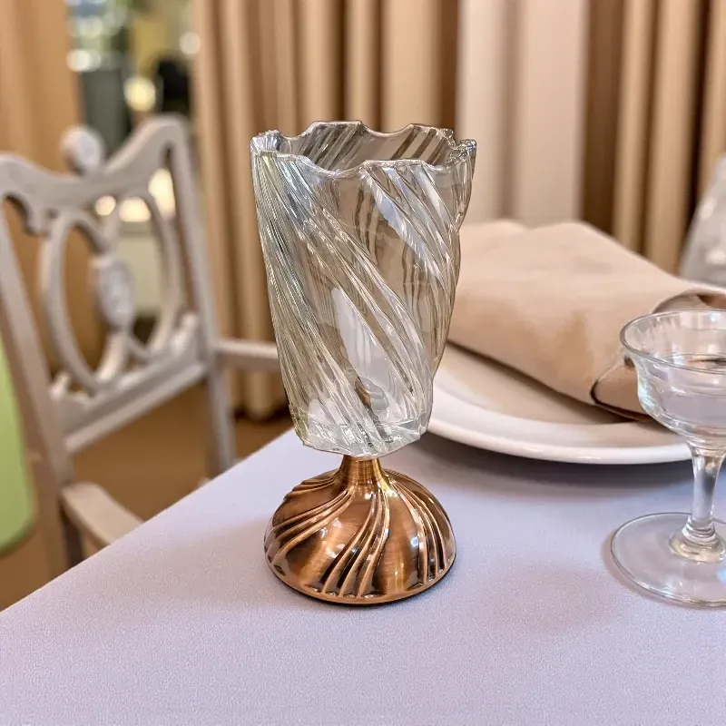 فازة كريستال حلزونية على قاعدة معدنية نحاسية على طاولة طعام