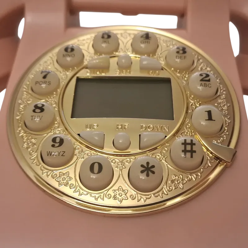 تليفون مكتبي وردي فاخر | تصميم كلاسيكي ذهبي مع شاشة عرض، موديل 030414 لقطة مقربة لقرص الأرقام الذهبي المزخرف، مع أزرار رقمية وشاشة عرض رقمية في المنتصف.