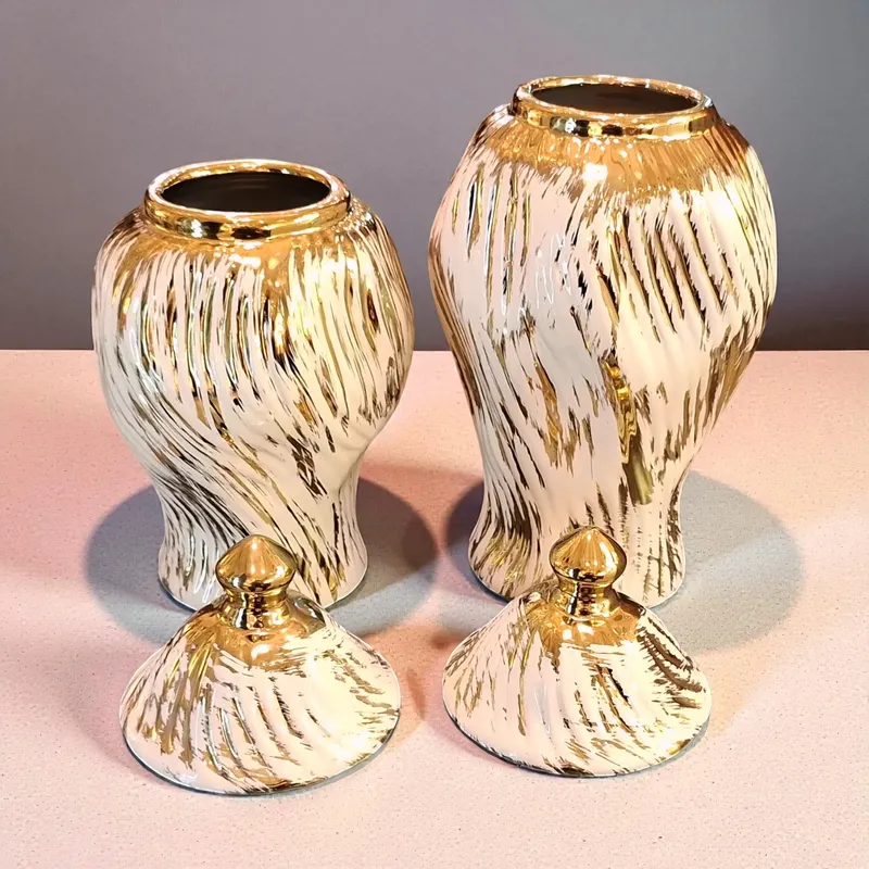 فازات زنجبيل سيراميك بيضاء وذهبية لامعة مفتوحة مع الأغطية الذهبية موضوعة جانباً، تُظهر لمعان الطلاء وجودة التصميم.