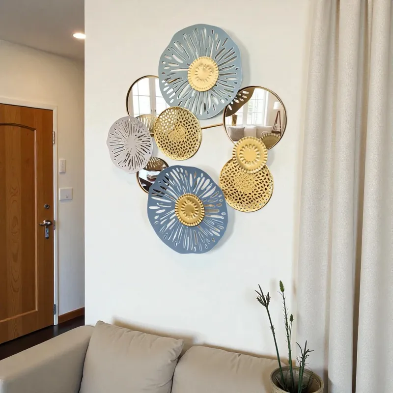لوحة حائط معدنية فنية على شكل زهور ومرايا، معروضة في مدخل منزل عصري فوق أريكة بلون البيج الفاتح.