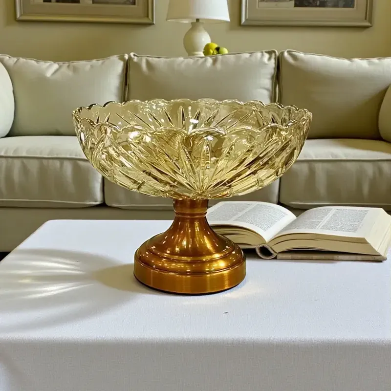 طبق فاكهة كريستال عسلي بنقوش بارزة وقاعدة ذهبية على ترابيزة بمفرش