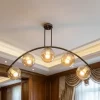 نجفة مودرن بتصميم قوس معدني زيتوني يحمل 5 كرات زجاجية عسلية.