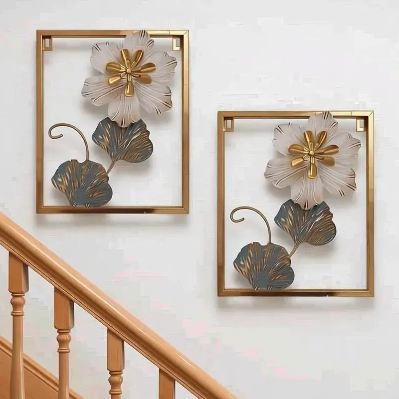 لوحة حائط معدنية بتصميم زهرة بيضاء وإطار ذهبي، ارتفاع 30 سم، موديل 030949 طقم لوحات حائط معدنية بتصميم زهور بيضاء منسقة بشكل ديكوري على جدار بجانب سلم داخلي.