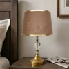 أباجورة معدنية بالكريستال فاخرة تتميز بغطاء كتان باللون البني، وتصميم عصري. قاعدة معدنية ذهبية متينة تضمن ثبات المصباح. مثالية للاستخدام في غرفة المعيشة أو غرفة النوم أو أي مكان آخر في منزلك.