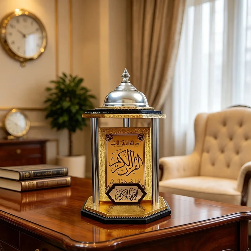 حامل مصحف فاخر بقاعدة ثمانية ذهبية وسوداء وقبة فضية يعرض مصحفاً ذهبياً على مكتب خشبي.