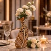 فازة خزفية فاخرة باللون الذهبي بتصميم ريشة مرصعة بالكريستال تحتوي على ورود بيضاء على طاولة طعام
