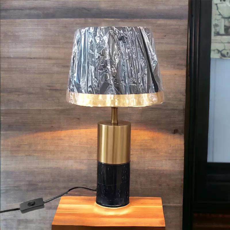 أباجورة مبتكرة بشكل أسطوانى وهيكل رخامى باللون الأسود فى الذهبى مع غطاء باللون الأسود وإطار ذهبى