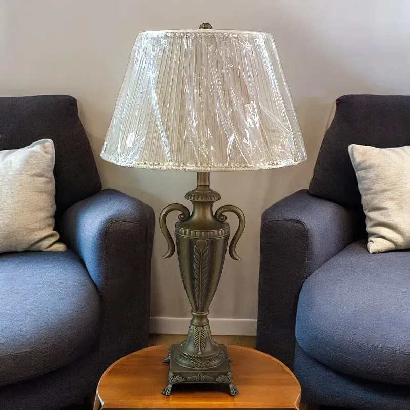 أباجورة على شكل كأس مصنوعة من المعدن باللون النحاسى عالي الجودة. تتميز الأباجورة بغطاء (شابوه) بليسيه بيج كلاسيكي ينشر ضوءًا ناعمًا ومريحًا.