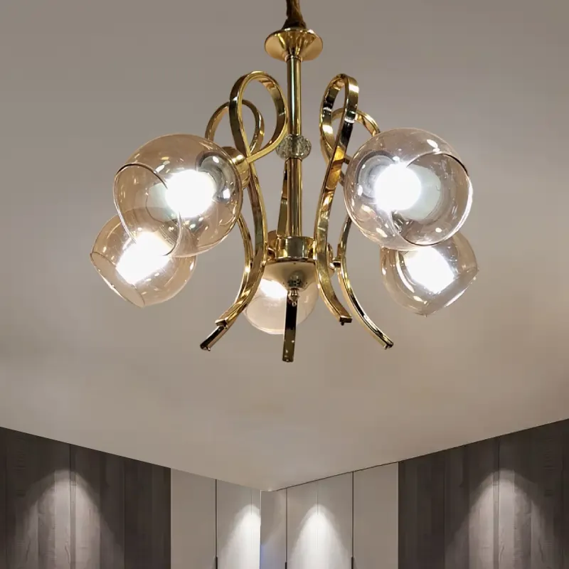 نجفة ذهبية أنيقة بتصميم كلاسيكي ب 5 كلوبات عسلية تعكس الأناقة والرقي. مثالية لإضفاء لمسة دافئة وجذابة على أي غرفة معيشة أو غرفة نوم. وتظهر مضاءة داخل الغرفة