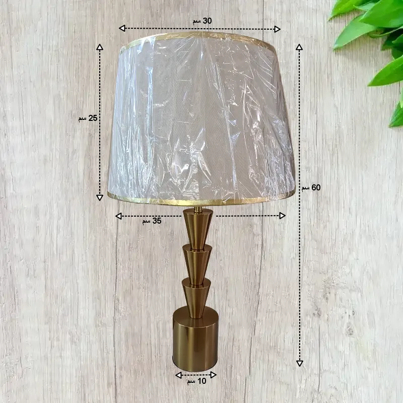 صورة توضيحية لأبعاد الأباجورة القياسية. تتتضمن قياسات قطر القاعدة وارتفاع الأباجورة. كما تتضمن عرض وارتفاع الغطاء. وتتضمن أيضًا تسميات لكل قياس.