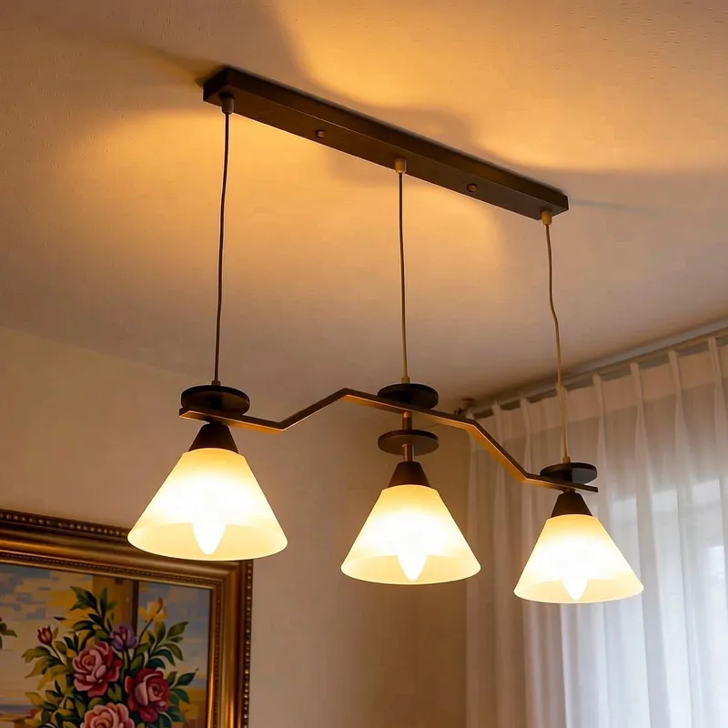 نجفة مودرن 3 كلوبات مضاءة باللون النحاسي مع تفاصيل خشبية سوداء لديكور المنزل.