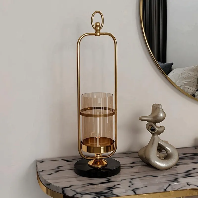 حامل شموع مودرن ذهبي بإطار جرس وقاعدة رخام أسود فاخرة، ارتفاع 52 سم، موديل 030887 حامل شموع ذهبي فاخر بتصميم جرس وقاعدة سوداء بجانب مرآة دائرية.