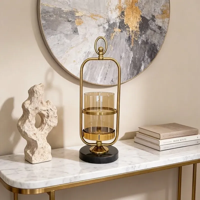 حامل شموع مودرن ذهبي بإطار جرس وقاعدة رخام أسود فاخرة، ارتفاع 39 سم، موديل 030888 حامل شموع ذهبي فاخر بتصميم جرس وقاعدة سوداء على سطح رخامي بجوار يمثال تجريدي.